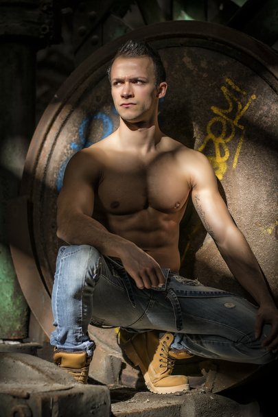Muscular shirtless young man in abandoned industrial warehouse - Valokuva, kuva