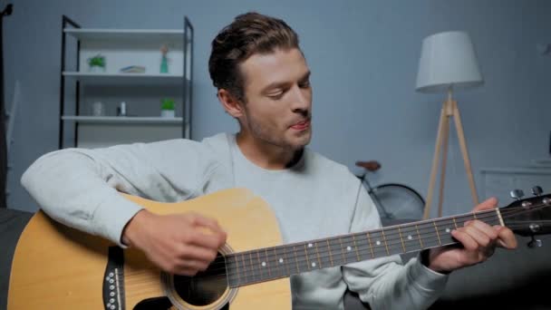 νεαρός άνδρας τραγουδά ενώ παίζει ακουστική κιθάρα κατά τη διάρκεια skype κλήσης στο σπίτι - Πλάνα, βίντεο