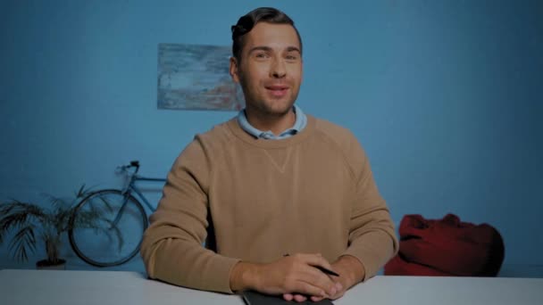 szczęśliwy człowiek z piórem gestykulacji i rozmowy podczas rozmowy skype w salonie - Materiał filmowy, wideo