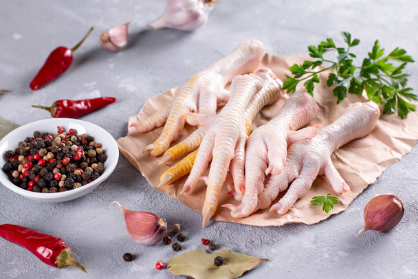 Hühnerfüße (Hühnerknochen), Gemüse, Gewürze und Kräuter für die Brühe auf grauem Hintergrund. Natürliches Kollagen tierischen Ursprungs - Foto, Bild