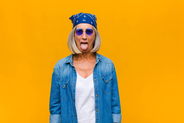 middle age woman with cheerful, carefree, rebellious attitude, joking and sticking tongue out, having fun - 写真・画像