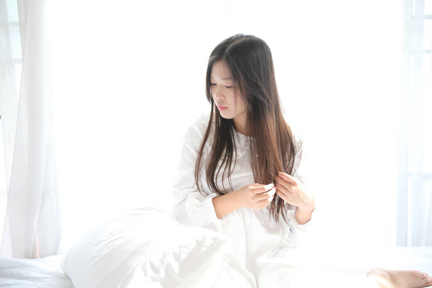 chica sentada con almohada en el dormitorio blanco - Foto, imagen