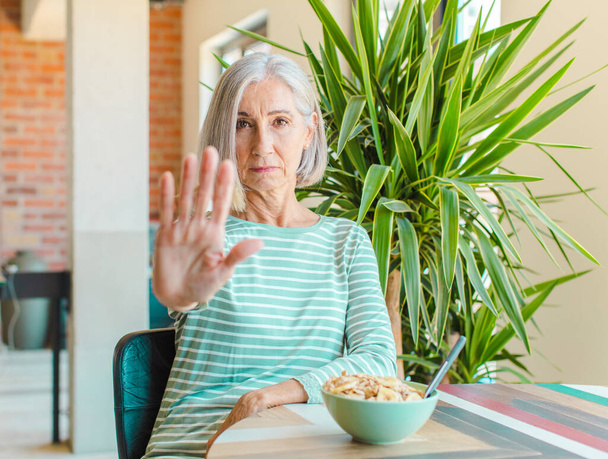 middle age woman looking serious, stern, displeased and angry showing open palm making stop gesture - Foto, Imagen