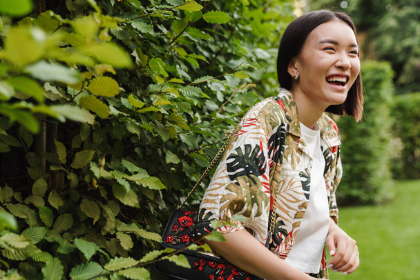Young beautiful asian woman laughing while standing in park - Zdjęcie, obraz