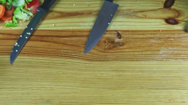 vista dall'alto sull'uomo a mano mette foglie di lattuga verde accanto a grandi coltelli sul tavolo - Filmati, video