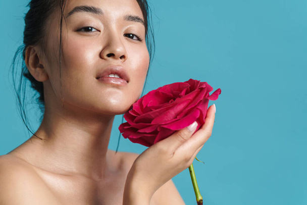Image of pleased shirtless asian girl posing with rose isolated over blue background - Фото, зображення