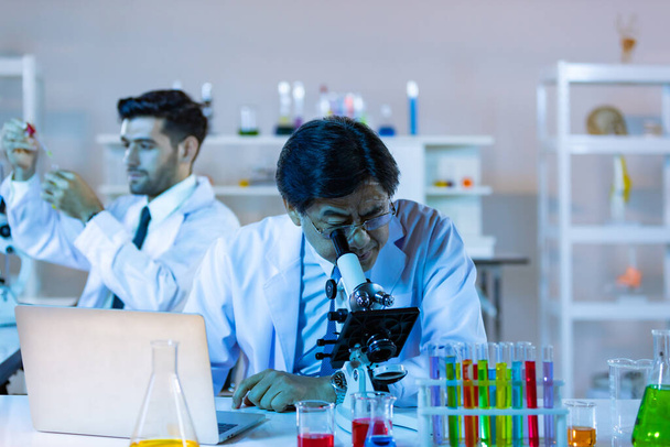 Mikrobiolog biotechnologický vědec nebo zdravotnický pracovník tým podívat mikroskop v laboratoři pro výzkum chemických dat asijských vědců. - Fotografie, Obrázek