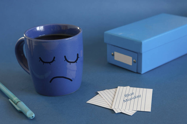 The beginning of the working day on blue Monday. Cup of tea, alarm clock and a note with the text Blue Monday. The most depressed day of the year - Foto, afbeelding