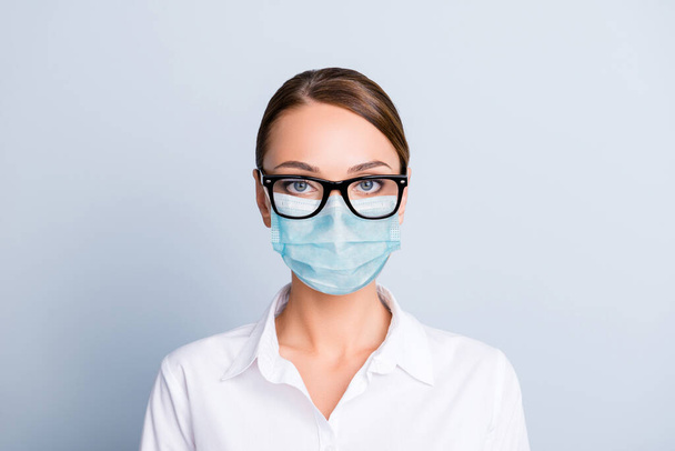 Close up portrait of concentrated woman with blue face mask isolated on gray background - Фото, изображение