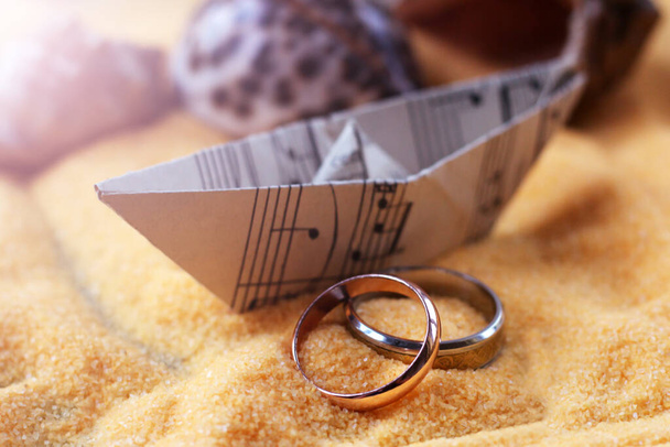 結婚指輪と砂の上に紙の音楽ノートで作られた船のモデル,夏 - 写真・画像