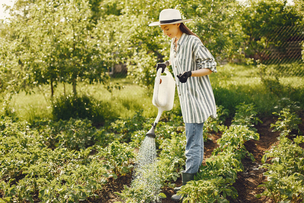 Woman in a hat holding funnel and works in a garden - Fotoğraf, Görsel