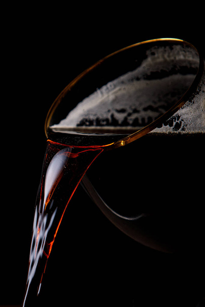Dark beer is pouring from the glass - Photo, Image