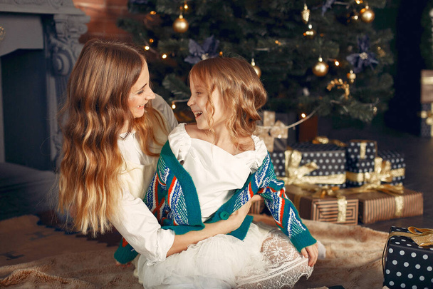 Mother with cute daughter at home near fireplace - Photo, Image