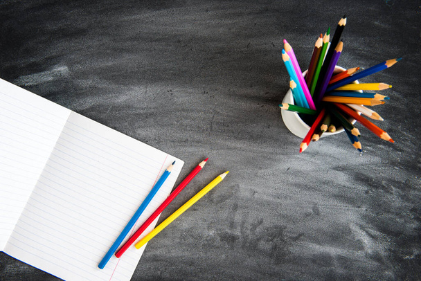 Crayons de couleur, copybook sur fond de tableau noir. Concept de retour à l'école. - Photo, image