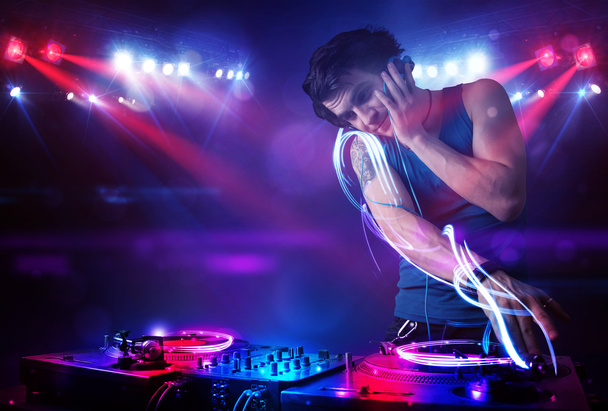 Disco jockey tocando música con efectos de haz de luz en el escenario
 - Foto, Imagen
