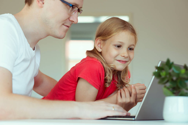 Happy young father with cute doughter learning together online at homeschooling - Fotoğraf, Görsel