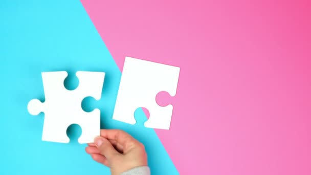 carta vuota pezzi bianchi di puzzle in mani femminili, puzzle collegato, sfondo colorato, vista dall'alto - Filmati, video