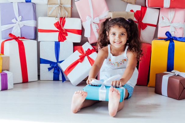 Красива маленька кучерява дівчинка і багато подарунків на день народження
 - Фото, зображення