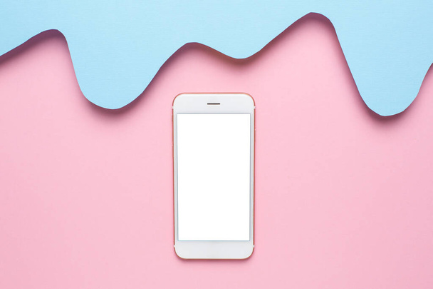 Mobiele telefoon en abstract papier gesneden blauwe golven kunst op roze achtergrond, pastel kleuren en technologie bovenaanzicht - Foto, afbeelding