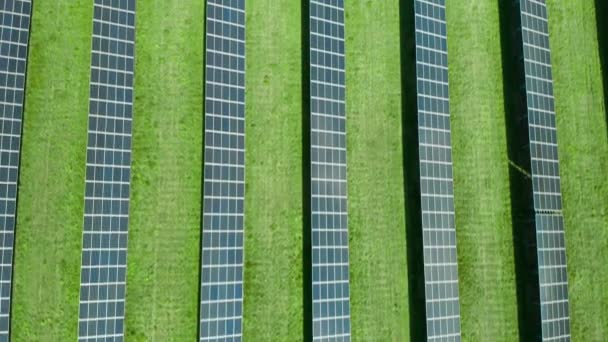 Repülés egy naperőmű felett elektromosság előállítására. Függőleges egyenes vonalak napelemek a zöld mezőben. Megújuló környezetbarát energiaforrás. - Felvétel, videó