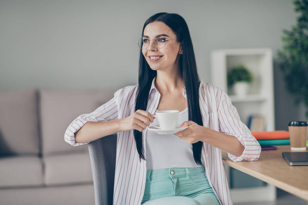 Photo of cheerful smiling woman broker sitting chair drinking tea looking empty space indoor workstation - Фото, изображение