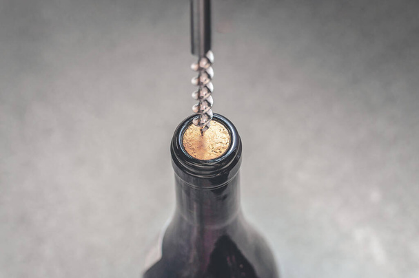 Aprire una bottiglia di vino con una vite di sughero. Vista dall'alto, toni di grigio, messa a fuoco selettiva - Foto, immagini