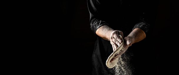 Beautiful and strong men's hands knead the dough make bread, pasta or pizza. Powdery flour flying into air. chef hands with flour in a freeze motion of a cloud of flour midair. - Photo, Image