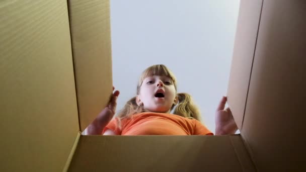 Dziecko otworzyło pudełko z prezentem. Mała dziewczynka zagląda do pudełka, jest zaskoczona i szczęśliwa, że ma niespodziankę. Zwolniony ruch. - Materiał filmowy, wideo