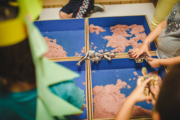 stampi per bambini da plastilina sul tavolo, Mani di bambini che giocano con argilla colorata, asilo nido da vicino, attività tattile con figure di dinosauro - Foto, immagini