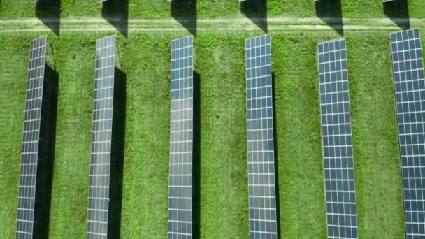 Repülés egy naperőmű felett elektromosság előállítására. Függőleges egyenes vonalak napelemek a zöld mezőben. Megújuló környezetbarát energiaforrás. - Felvétel, videó