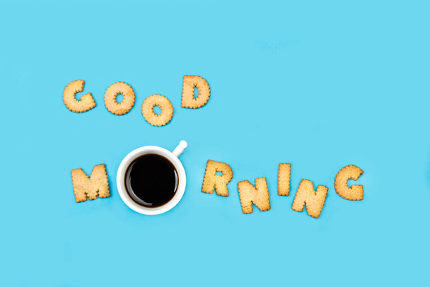 Hyvää huomenta aakkoset evästeet ja kuppi kahvia vaaleansinisellä taustalla ylhäältä katsottuna - Valokuva, kuva