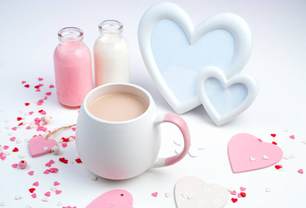 A Cup of coffee with milk, a frame in the shape of hearts and a bottle of milk on a white background with hearts. - Photo, Image