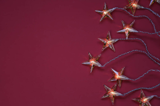 Top view of star shaped Christmas lights against red background with copy space - Photo, Image