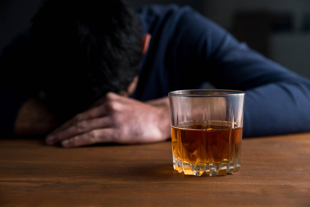 sad man with glass of whiskey on des - Valokuva, kuva