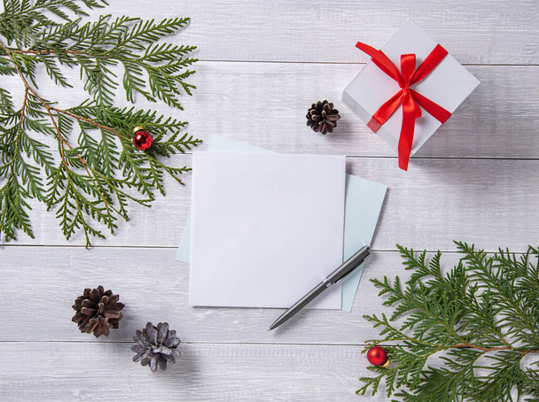  Χριστούγεννα επίπεδη θέσει με το γράμμα και το κουτί που υπάρχει στο φως ξύλινο τραπέζι. Χριστουγεννιάτικο φόντο με δέντρο, καραμέλα, παιχνίδια και κώνους. Άνω όψη  - Φωτογραφία, εικόνα