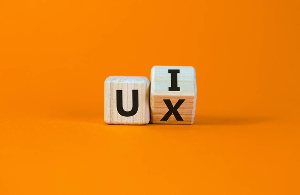 UX design or UI design. Turned cube and changed the words 'UX' to 'UI'. Beautiful orange background. Business concept. Copy space. - Foto, Imagem