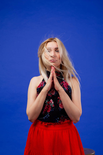Blonde on a blue background. Beautiful woman in an orange skirt in the studio. Blonde looking at the camera - Foto, immagini