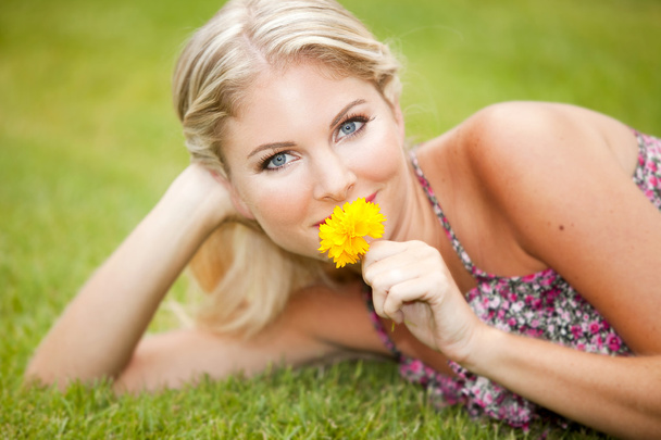 Kobieta na trawie z kwiatem - Zdjęcie, obraz