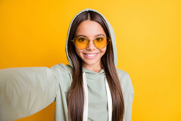 Photo of nice young girl smile make photo wear hood bright sunglass isolated on vibrant yellow color background - Fotografie, Obrázek