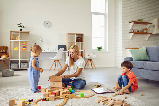 Mother playing educational games with smiling children on floor at home - Foto, Bild