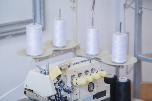 Overlock naaimachine op tafel bij atelier - kleermaker, ontwerper werkplek - Foto, afbeelding