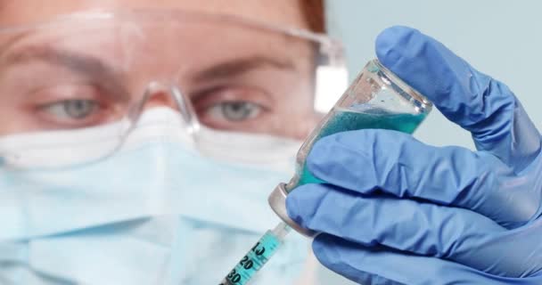 Врач или медсестра в защитной медицинской хирургической маске и синих нитрильных перчатках, держащих грипп, корь, коронавирусную вакцину для детской и взрослой вакцинации - Кадры, видео