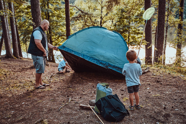 Preschool boys pitching a tent with their father in summer forest - Photo, Image