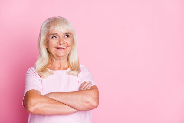 Photo portrait of elderly woman with folded hands looking at blank space isolated on pastel pink colored background - Fotoğraf, Görsel