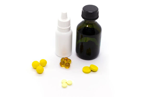 Pillole gialle, bottiglia con verde brillante, gocce nasali per il raffreddore comune su sfondo bianco - Foto, immagini