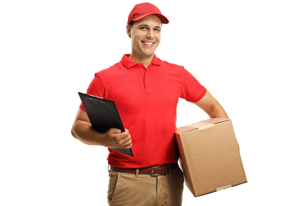 Male courier in a uniform holding a cardboard box and a clipboard isolated on white background - Foto, afbeelding