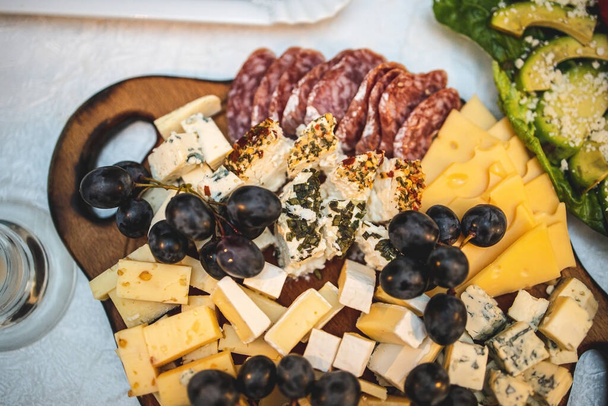 El queso y la bandeja de carne en una tabla de madera en una mesa festiva. Vista desde arriba. - Foto, imagen