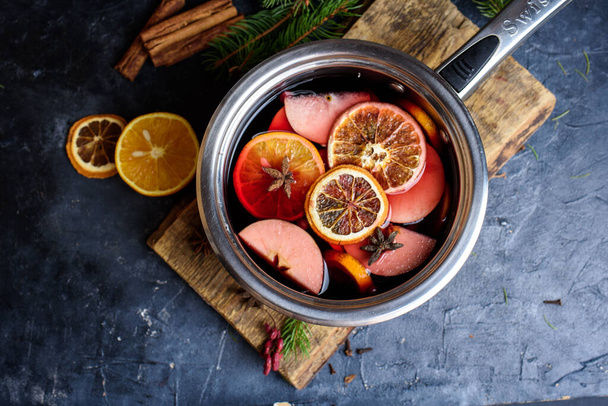 Making hot alcohol, mulled wine for sale at country fair. Glintwine from red wine with citrus and cloves in big metal stock pot, mixed with soup ladle. Closeup new years contnent - Photo, Image
