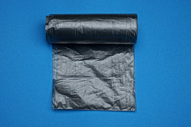 青いテーブルの上には黒いプラスチック製のセロハンゴミ袋が一つ - 写真・画像