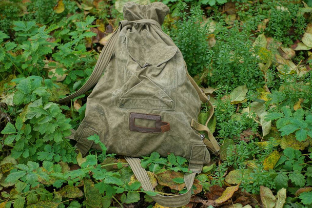 jeden radziecki stary wojsko pełny plecak torba stoi wśród zielonej roślinności i spadł liście w przyrodzie - Zdjęcie, obraz